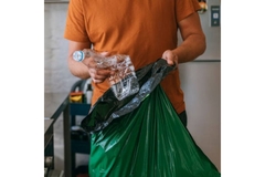 Image Person placing plastic bottle in trash bag